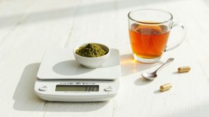 Kratom Active 30 Kitchen scale weighing kratom powder with tea and capsules — kratom dosage and how-to-use guide